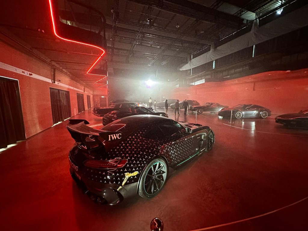 Moderne Eventlocation mit Luxusautos und atmosphärischer roter Beleuchtung bei einem exklusiven Event