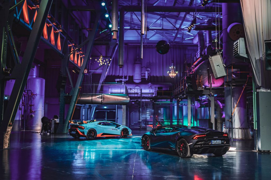Moderne Eventlocation mit zwei Sportwagen und farbiger Beleuchtung in industrieller Halle