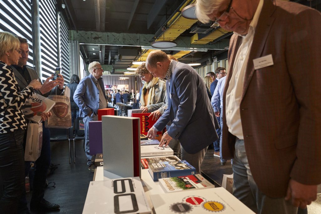 Menschen betrachten Bücher und Materialien auf einem Tisch bei einem Event in einer modernen Eventlocation mit Industriecharme