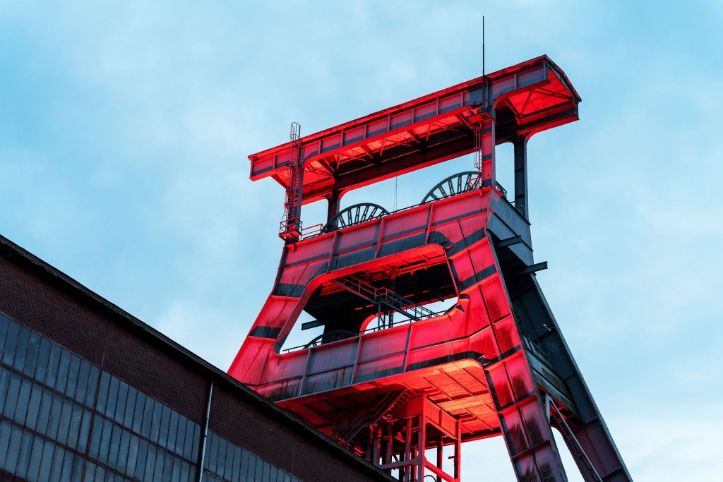 Leuchtend rotes Fördergerüst auf ehemaliger Zeche als markante Eventlocation vor blauem Himmel