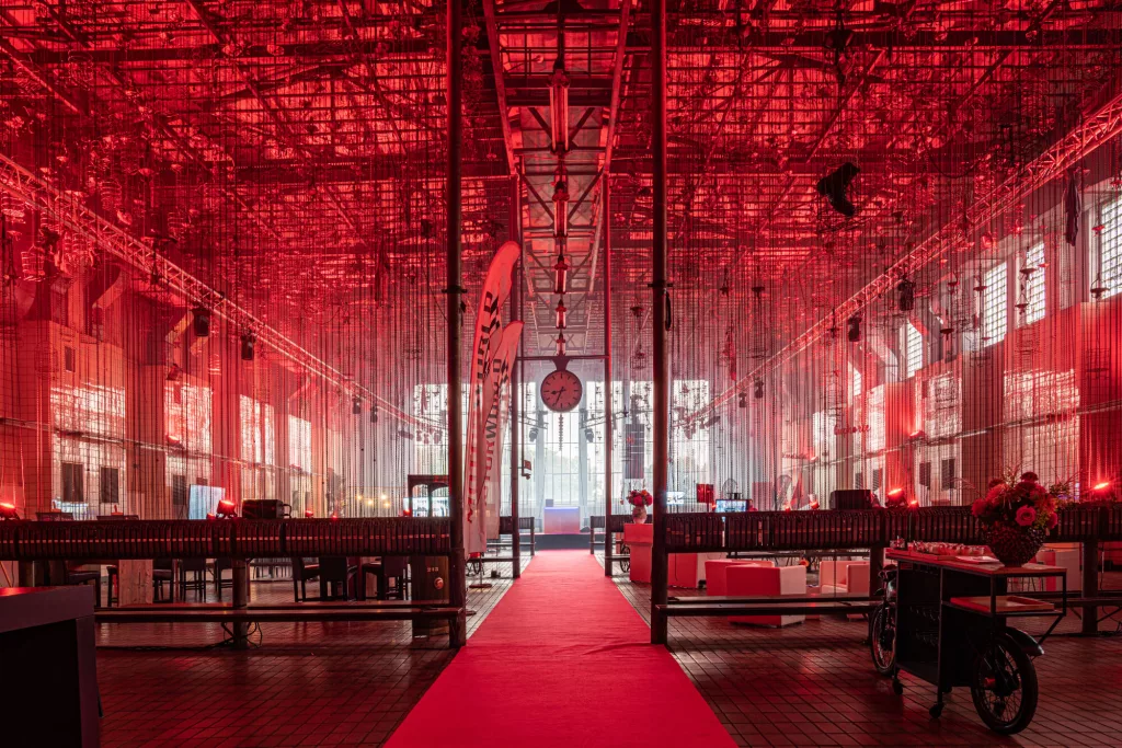 Rote Eventlocation mit rotem Teppich, modernem Mobiliar und dekorativer Beleuchtung in großer Halle