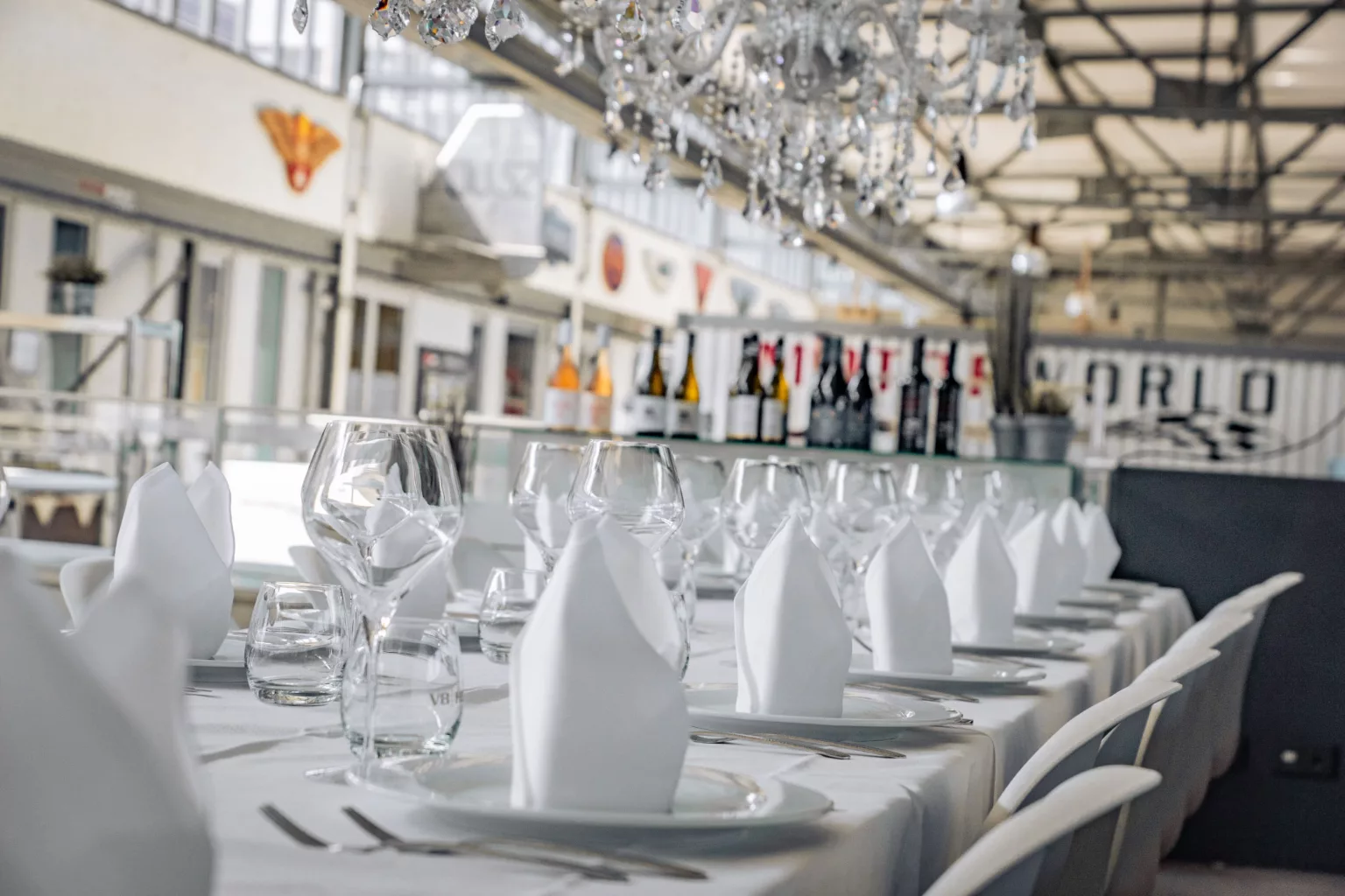 Elegant event location with festively laid table, wine glasses and napkins under a chandelier