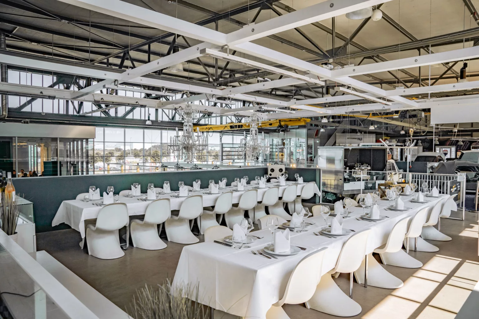 Modern event location with a long, white table and stylish white chairs in an industrial space