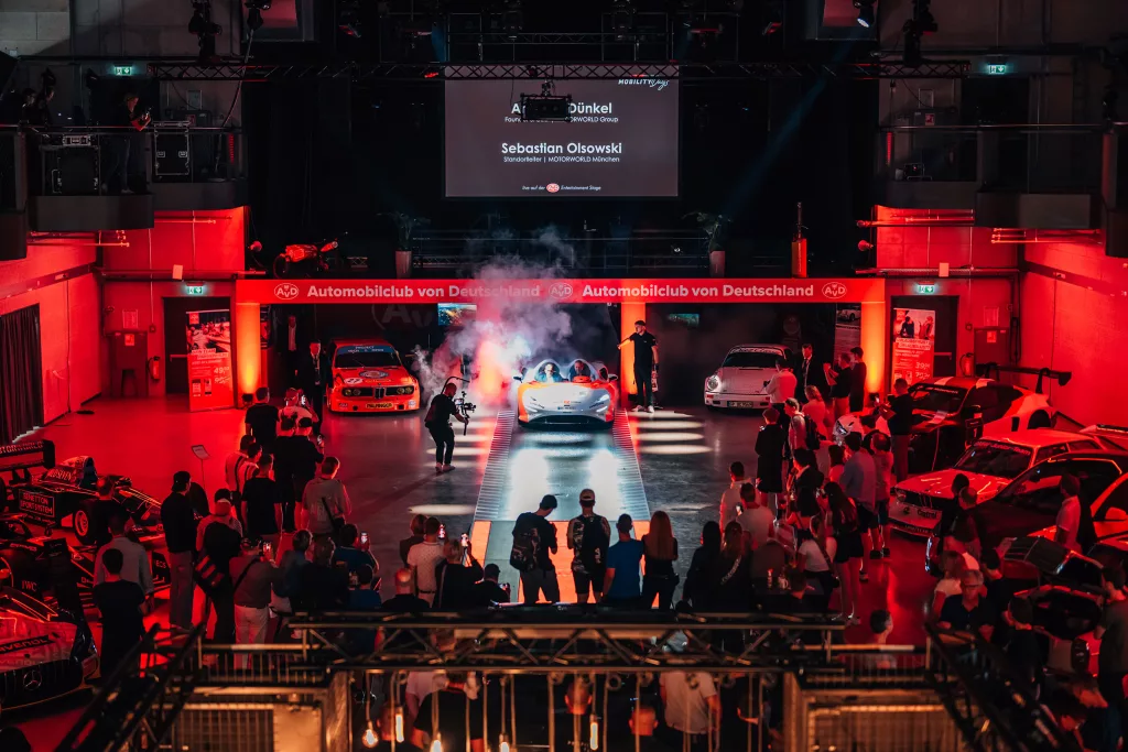 Eventlocation mit roter Beleuchtung präsentiert sportliche Autos vor Publikum bei Automobilclub von Deutschland Event
