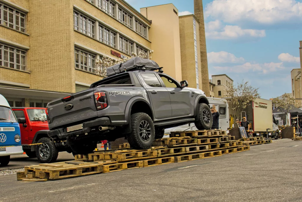 Geländewagen Ford Ranger Raptor fährt auf Palettenrampe bei Event vor Industriegebäude als Eventlocation