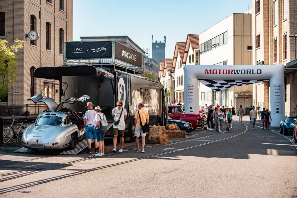 Event mit historischen Rennwagen und Besuchern an einer Eventlocation in einer urbanen Straße mit MOTORWORLD-Bogen