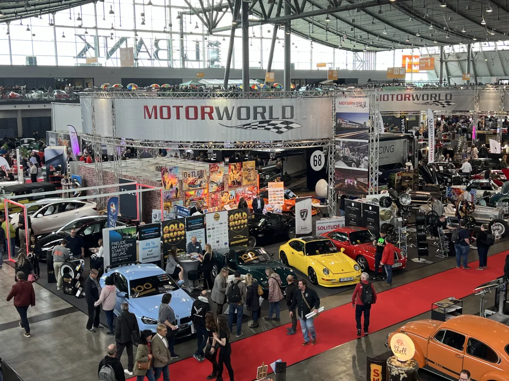Belebtes Event mit Motorworld-Stand und klassischen Autos in moderner Eventlocation mit vielen Besuchern