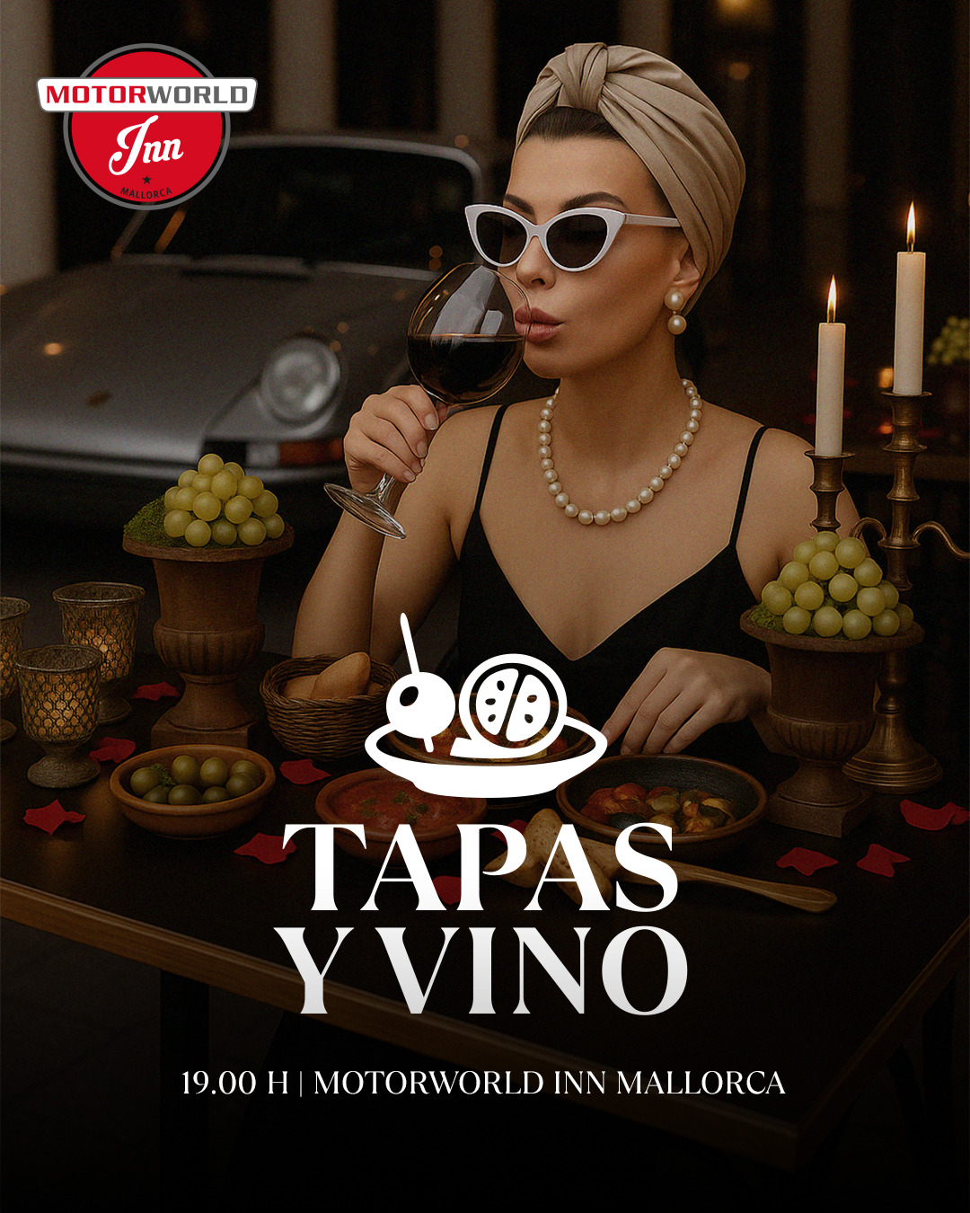 Elegante Frau mit Perlenkette und Haarband trinkt Rotwein an einem Tisch mit Kerzen und Trauben, im Hintergrund ein klassisches Auto; Text "Tapas y Vino" und Veranstaltungsdetails Motorworld Inn Mallorca 19:00 Uhr