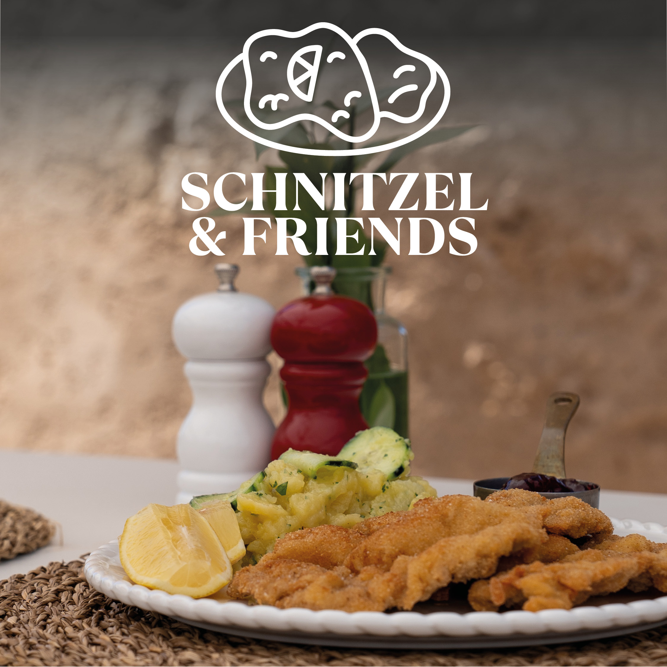 Vordergrund: Teller mit knusprig paniertem Schnitzel, Zitronenspalten und Kartoffelsalat; im Hintergrund Salz- und Pfeffermühlen, Glasvase und darüber weißes Logo „SCHNITZEL & FRIENDS“ mit stilisierter Schnitzel-Illustration.