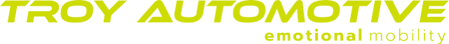 Logo with TROY AUTOMOTIVE lettering in yellow-green, angular, cursive typography and small slogan emotional mobility.