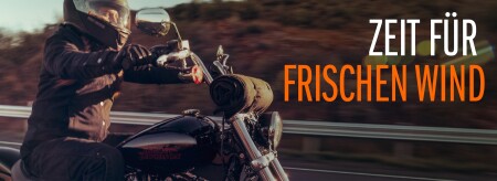 Biker mit Helm fährt Motorrad auf einer Straße, rechts der Schriftzug „Zeit für frischen Wind“.