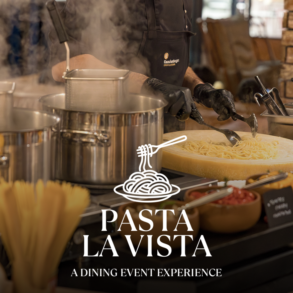 Chef stirring pasta in a hollowed-out Parmesan ball next to steaming pots, "Pasta La Vista" lettering visible.