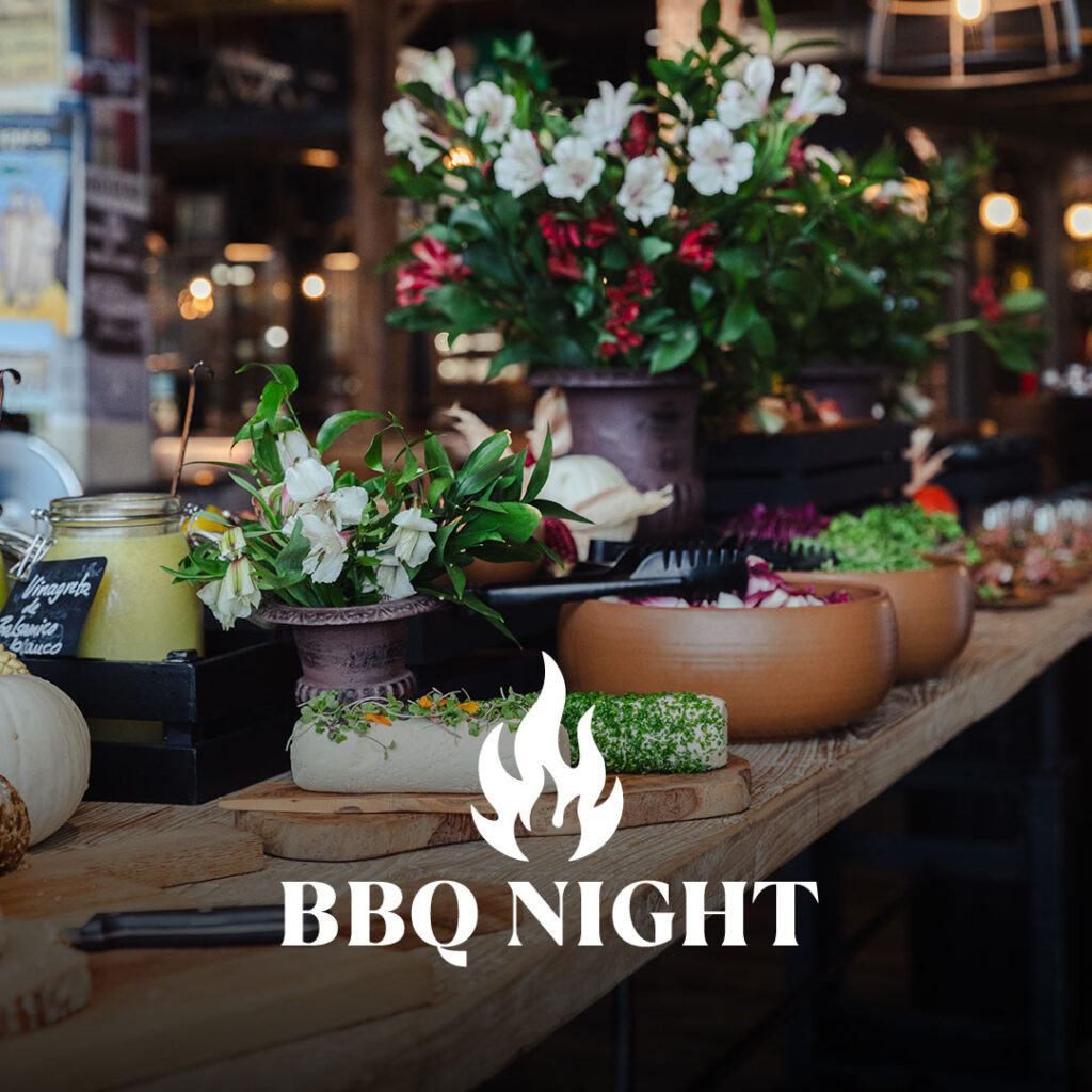 Buffet mit Blumenarrangements, Schalen mit Salaten und Käse auf einem rustikalen Holztisch, Text "BBQ NIGHT".