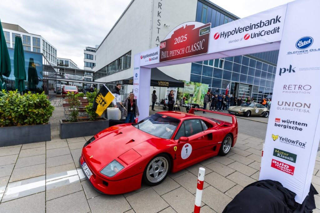 Roter Ferrari F40 mit Startnummer bei einem klassischen Autoevent unter einem Banner "Paul Pietsch Classic 2025", Zuschauer im Hintergrund