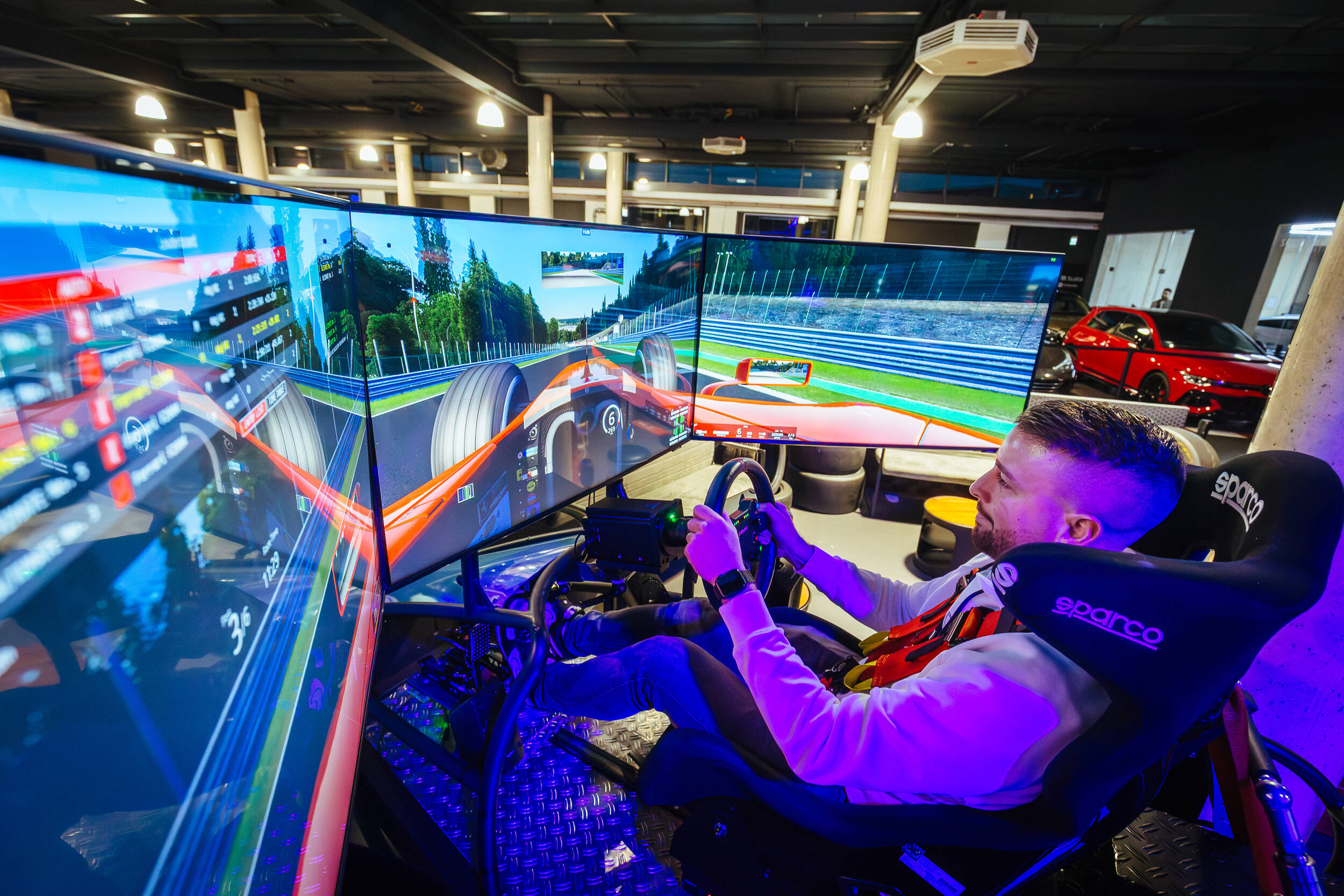 Mann fährt im Rennsimulator mit drei Monitoren in einem modernen Showroom