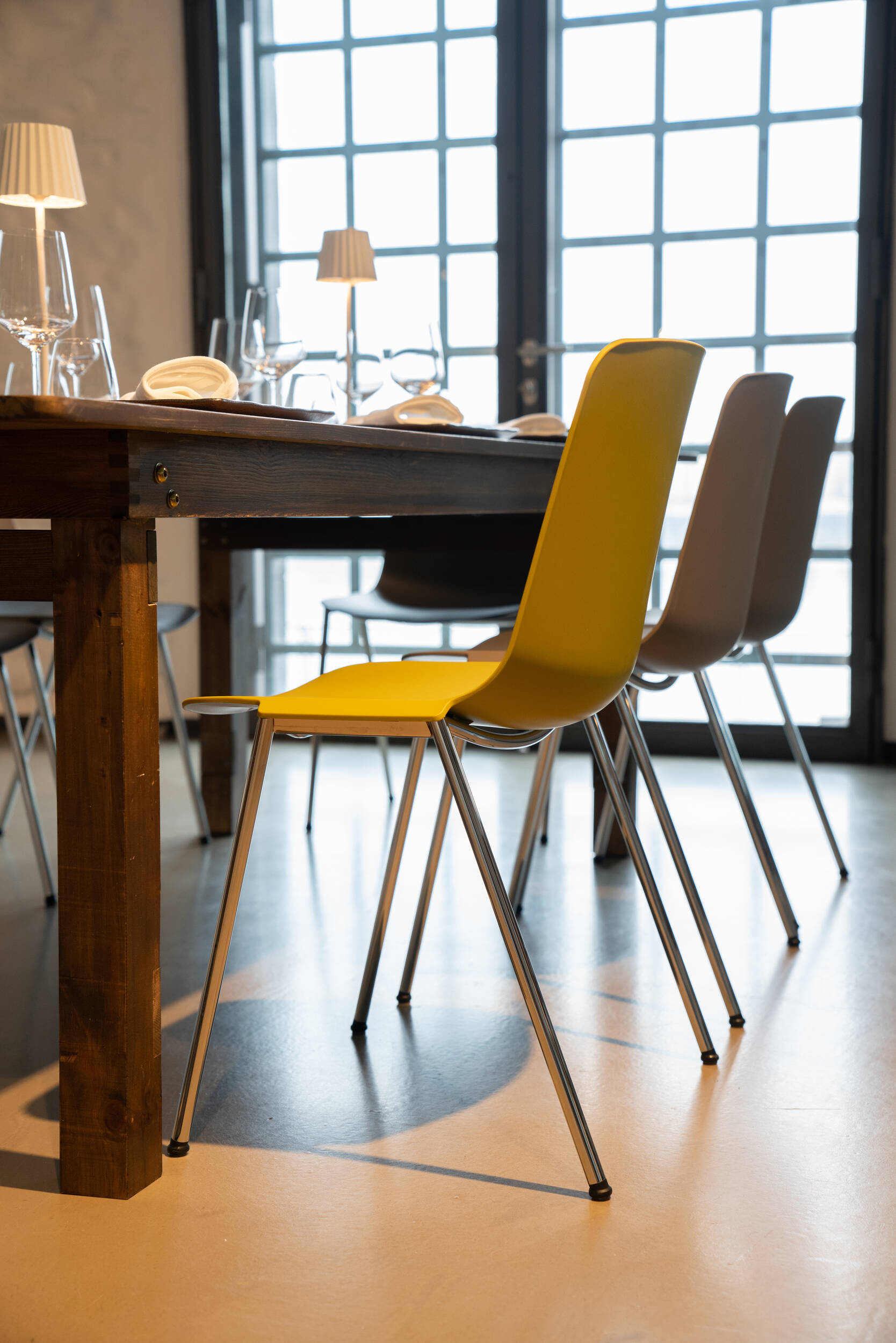 Moderne Stühle an einem gedeckten Holztisch im hellen Esszimmer