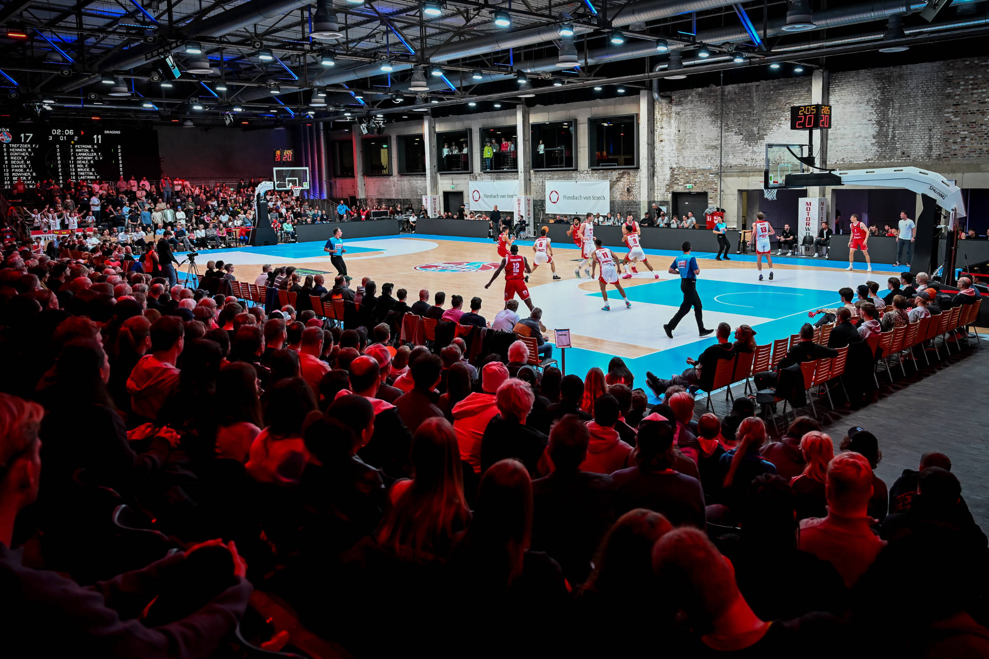 Basketballspiel in einer vollen Halle mit jubelndem Publikum und laufender Aktion auf dem Spielfeld