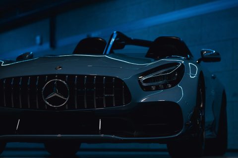 Frontansicht eines weißen Mercedes-Sportwagens in einer dunklen Garage mit blauem Licht